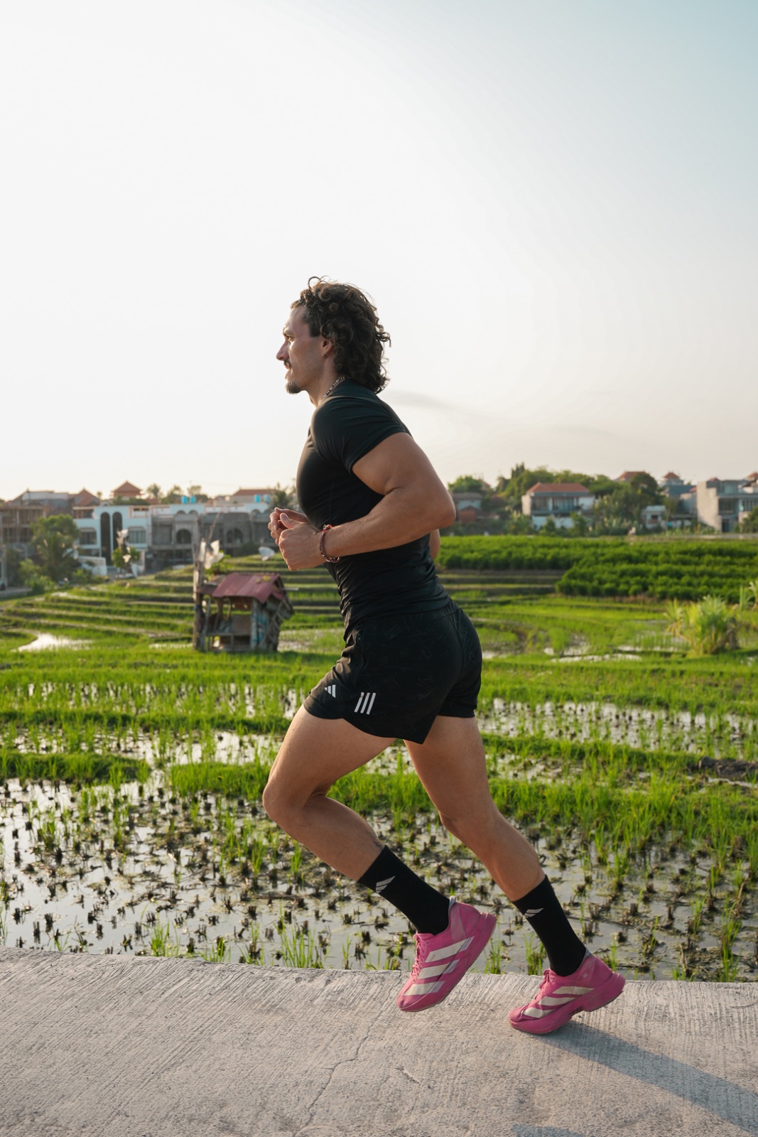 Miguel corriendo cuesta arriba por un camino entre arrozales